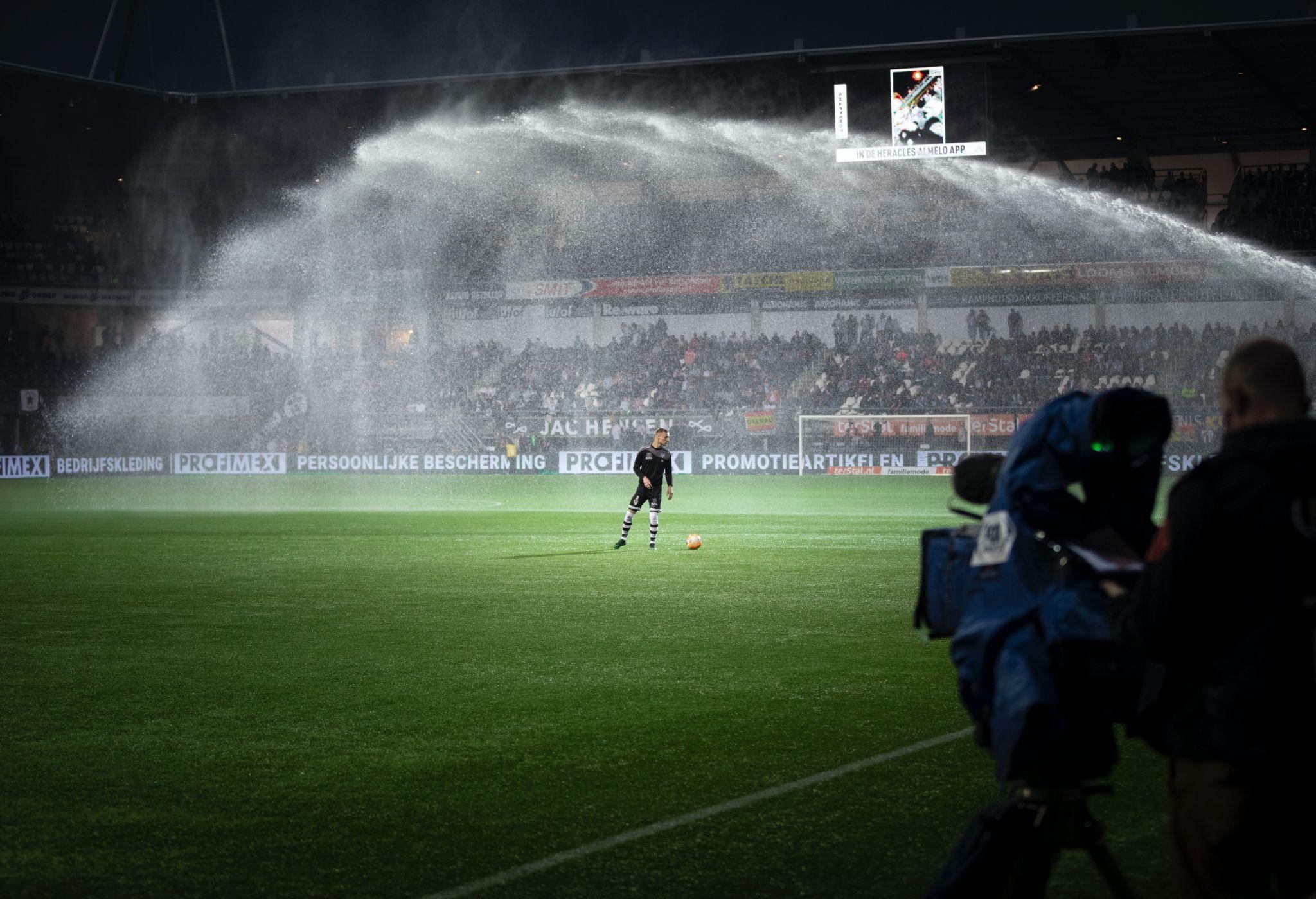 A soccer player standing on a football field enduring the rain during a match
